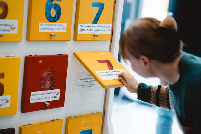 Eine Person betrachtet interaktive Tafeln mit nummerierten Klappen, von denen eine geöffnet ist und Text enthüllt.