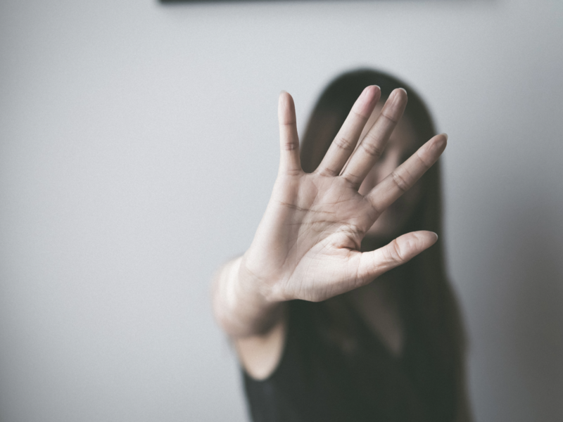 Eine Person steht in einem unscharfen Hintergrund und hält eine Hand offen in Richtung Kamera.