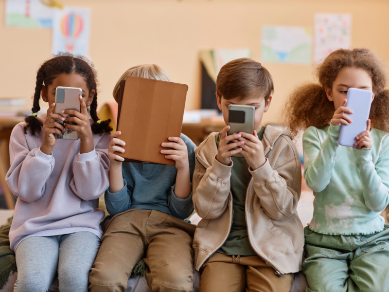 Vier Kinder die alle ein Smartphone oder Tablet in den Händen halten