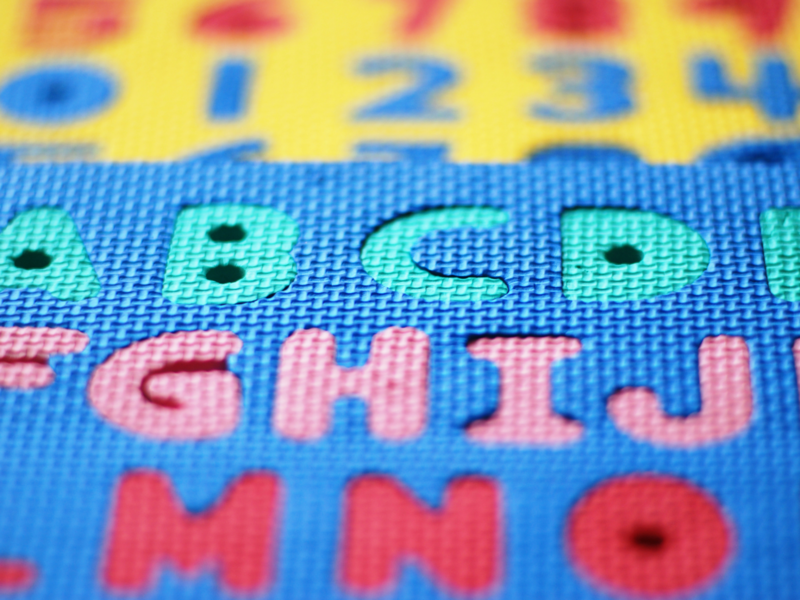 Nahaufnahme von bunten Schaumstoff-Puzzlematten mit ausgestanzten Buchstaben und Zahlen.