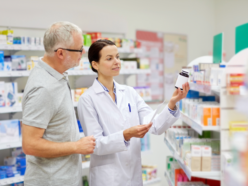 Eine Apothekerin zeigt einem Mann in der Apotheke ein Medikament